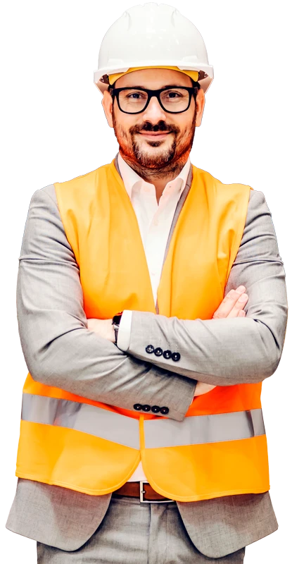 Hombre vestido de traje y con chaleco y casco de seguridad propios de un ambiente de trabajo de almacén o fábrica